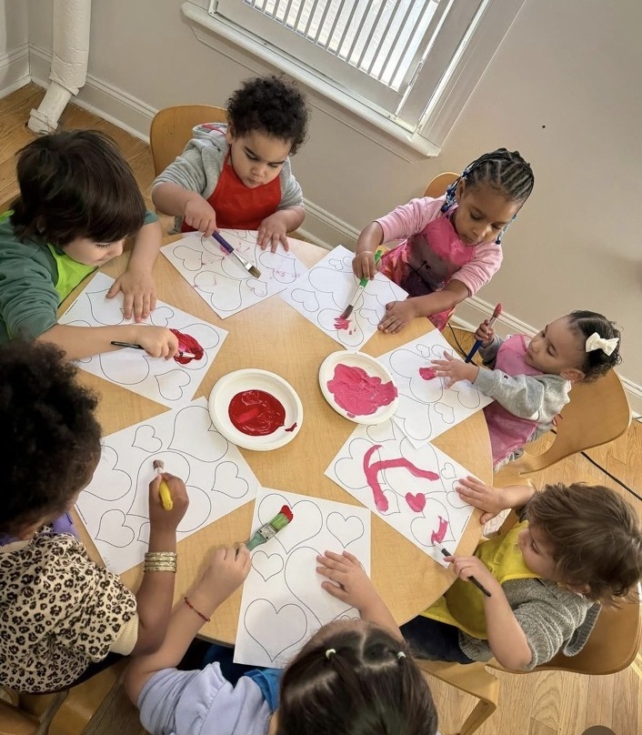 Children painting hearts together during a hands-on classroom activity
